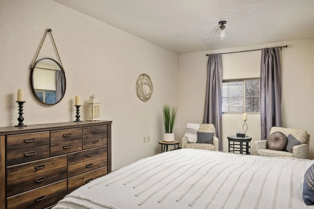 This photo features a tranquil seating nook with a dresser, mirror, window, and a seating area, all basked in soft natural light. The mood is peaceful and cozy, suggesting a space for relaxation and unwinding.