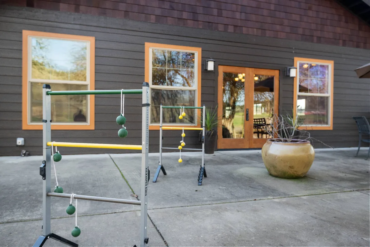 Two colorful ladder toss games are set up on a lush lawn near the home's inviting patio entrance, suggesting playful afternoons and outdoor fun. The scene is lively and welcoming, perfect for guests of all ages.